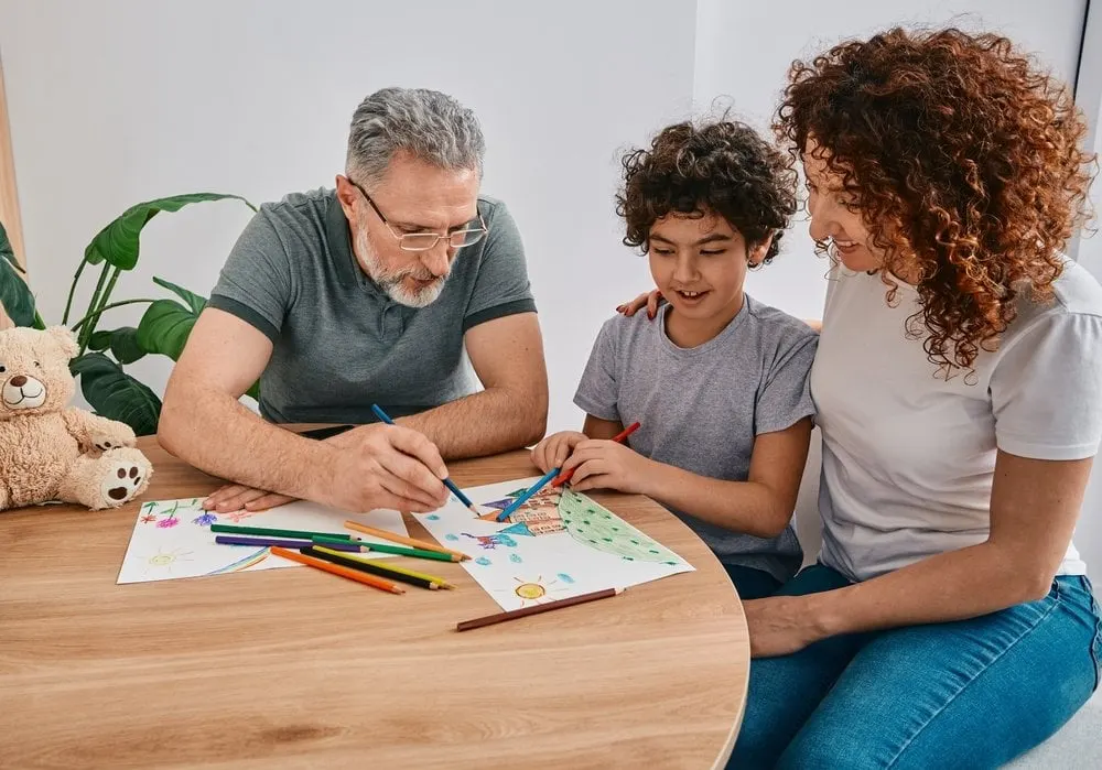 A father, mother and son coloring together at a table